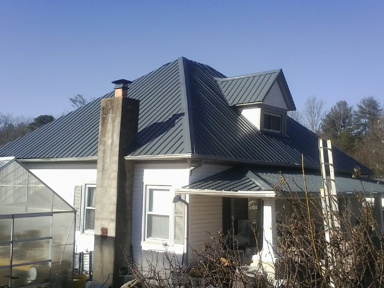 Dark blue standing seam metal roof on a white farmhouse with dormer — Slate & Tile Roof Repair by Roofing Brothers in Hookstown