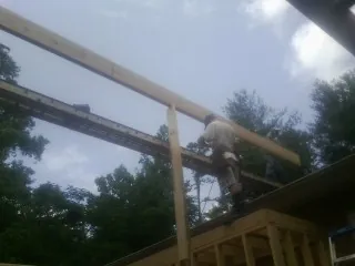Carpenter setting a ridge beam over a new addition frame — Ice Dam Removal by Roofing Brothers in Hookstown