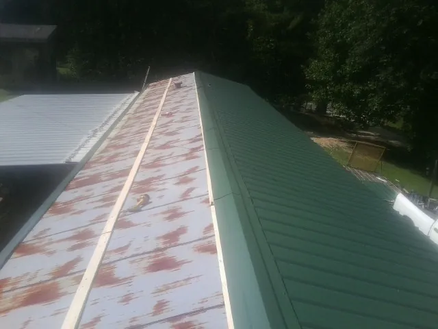 Old rusted panels beside newly installed green metal roofing — Wind Damage Roof Repair by Roofing Brothers in Hookstown