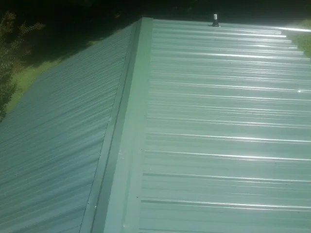 New green metal panels meeting at the ridge of a roof — Flat Roof Repair work by our crew in Hookstown