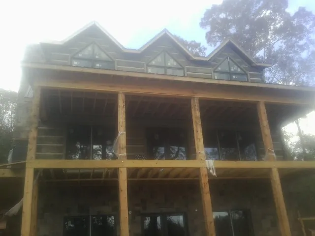 Dormers and porch framing on a large log home under construction — Roof Coating work by our crew in Hookstown