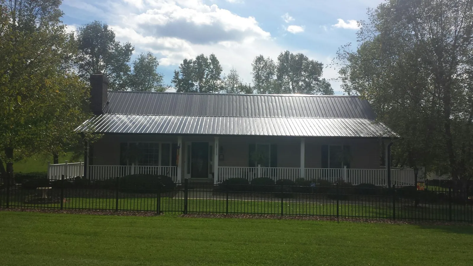 Gray metal roof on a brick ranch with a full width front porch — Gutter Guard Installation work by our crew in Hookstown