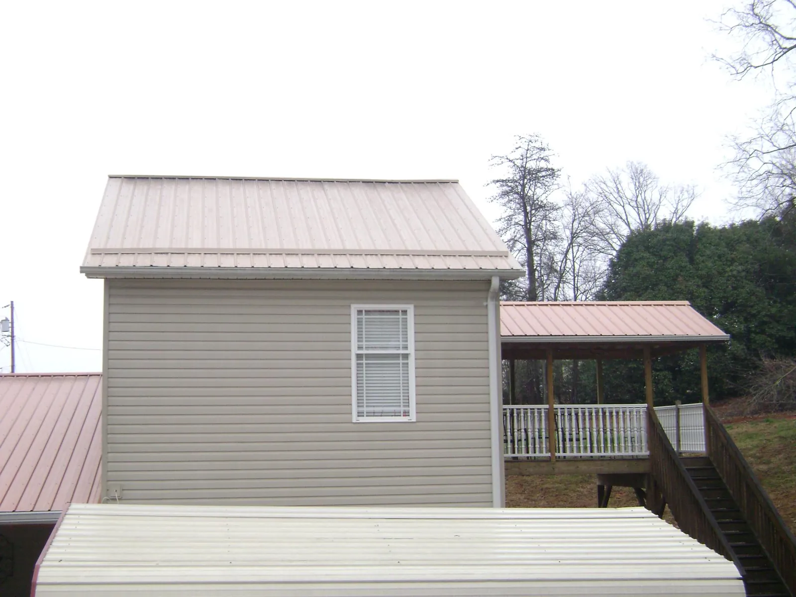 Tan metal roofs on a two story addition and attached porch, from a Roof Replacement job in Hookstown